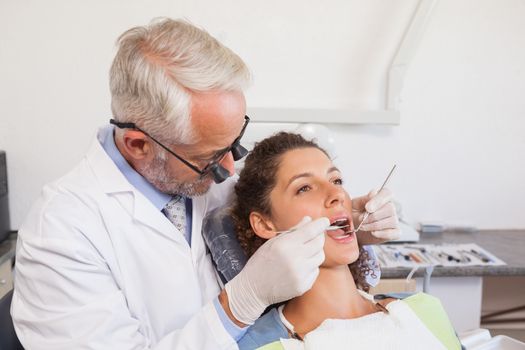 Dentist examining a patients teeth in the dentists chair at the dental clinic