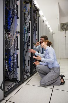 Team of technicians kneeling and looking at servers in large data center