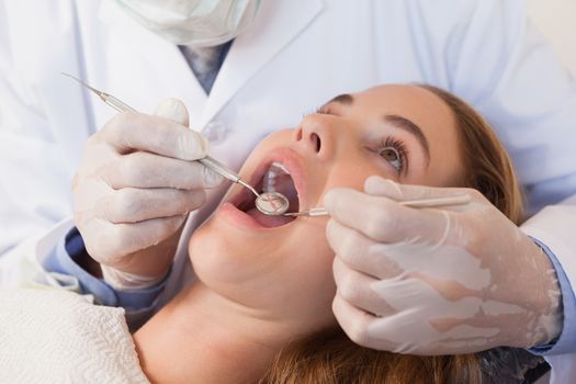 Dentist examining a patients teeth in the dentists chair at the dental clinic