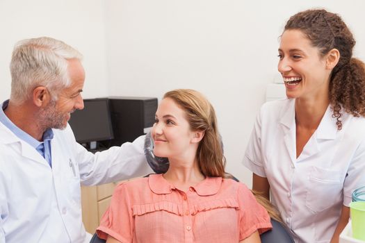 Dentist and assistant smiling with patient in chair at the dental clinic