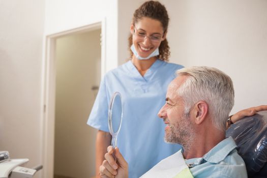 Dentist showing patient his new smile in the mirror at the dental clinic