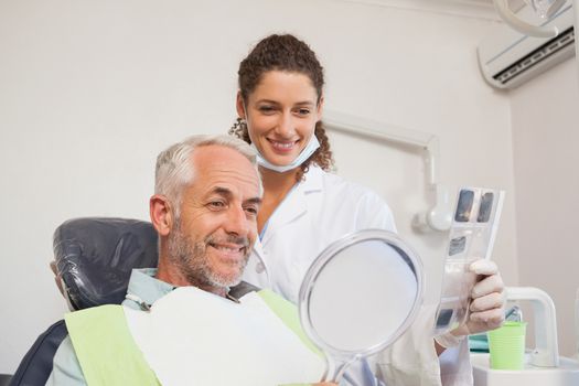 Patient admiring his new smile in the mirror at the dental clinic