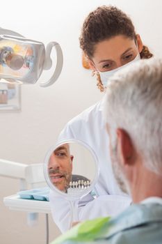 Patient admiring his new smile in the mirror at the dental clinic