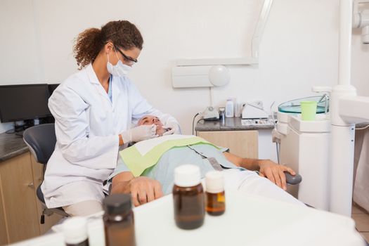 Dentist examining a patients teeth in the dentists chair at the dental clinic