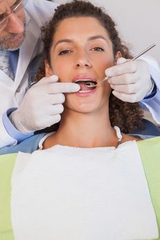 Dentist examining a patients teeth in the dentists chair at the dental clinic