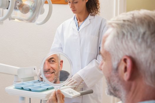 Patient admiring new smile in the mirror at the dental clinic