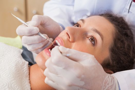 Dentist examining a patients teeth in the dentists chair at the dental clinic