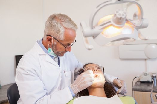 Dentist examining a patients teeth in the dentists chair at the dental clinic