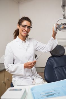 Dentist holding drill smiling at camera at the dental clinic