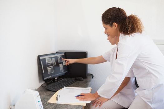 Dentist and assistant studying x-rays on computer at the dental clinic