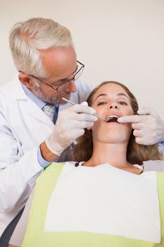 Dentist examining a patients teeth in the dentists chair at the dental clinic
