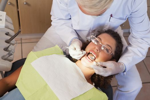 Dentist examining a patients teeth in the dentists chair at the dental clinic