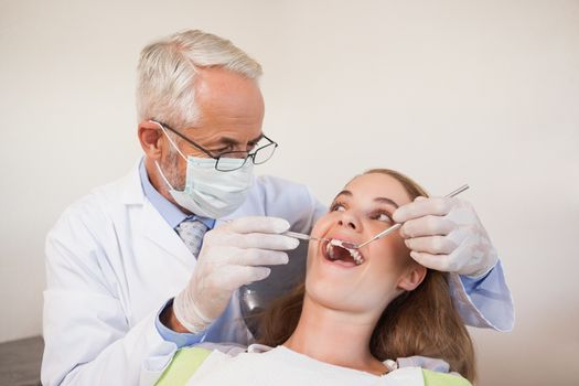 Dentist examining a patients teeth in the dentists chair at the dental clinic