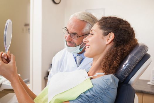 Patient admiring her new smile in the mirror at the dental clinic