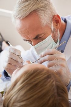 Dentist examining a patients teeth in the dentists chair at the dental clinic