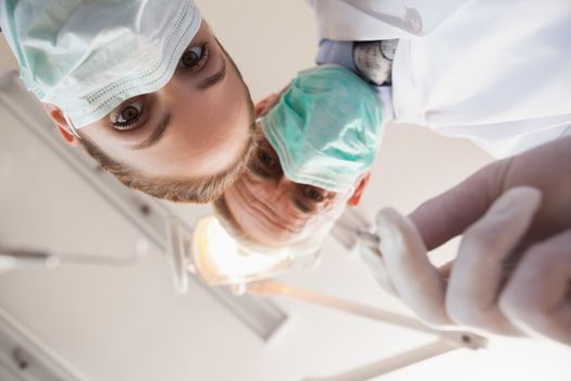 Dentist and assistant leaning over patient at the dental clinic