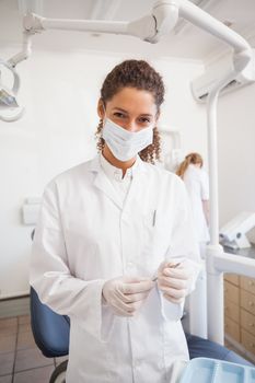 Dentist examining her tools on a tray looking at camera at the dental clinic