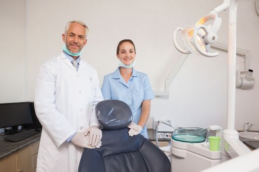Dentist and assistant smiling at camera at the dental clinic