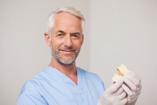 Dentist in blue scrubs holding mouth model at the dental clinic