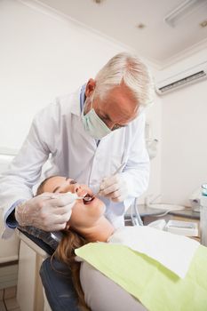 Dentist examining a patients teeth in the dentists chair at the dental clinic