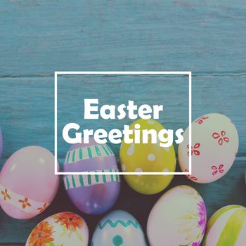 Easter greeting against painted easter eggs on wooden surface