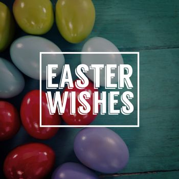 Easter greeting against colorful easter eggs on wooden surface