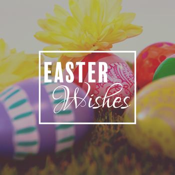 Easter greeting against painted easter eggs with flowers on grass