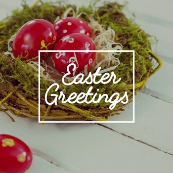 Easter greeting against red easter eggs in nest on wooden surface