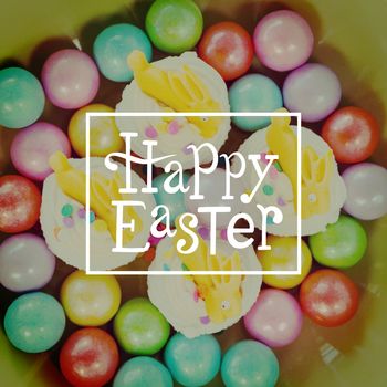 Happy easter against colorful chocolates and cupcakes in bowl
