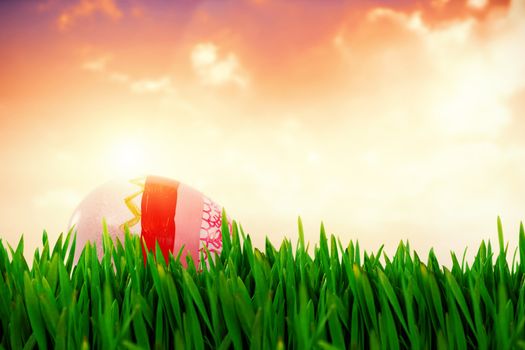 Grass growing outdoors against painted easter eggs on white background