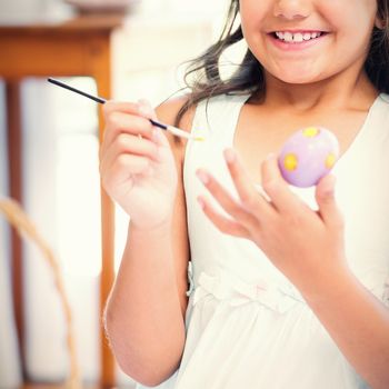 Cute girl painting easter eggs in the living room