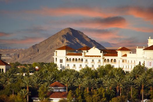 A white stucco luxury resort at the foot of a mountain in the desert