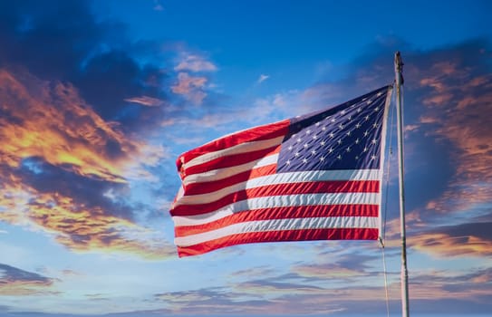 An American flag blowing in the wind against a clear blue sky