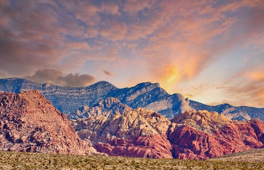 Red rock hills and distant mountains behind the desert