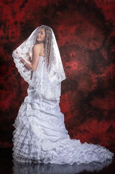 Young beautiful woman in a wedding dress on a studio background