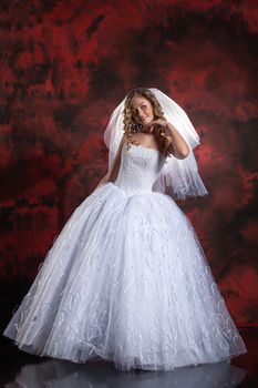 Young beautiful woman in a wedding dress on a studio background