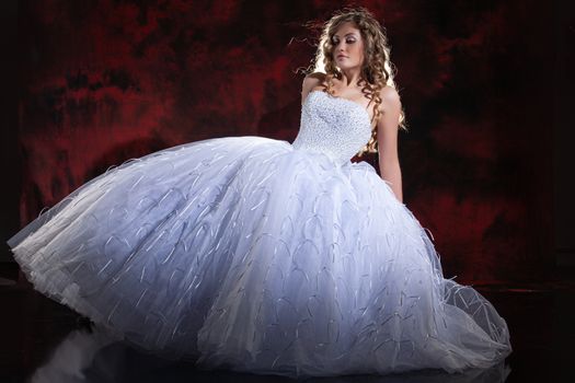 Young beautiful woman in a wedding dress on a studio background