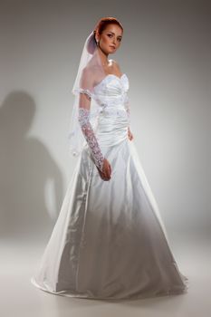 Young beautiful woman in a wedding dress on a studio background