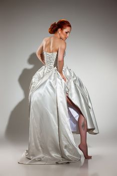 Young beautiful woman in a wedding dress on a studio background