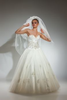 Young beautiful woman in a wedding dress on a studio background