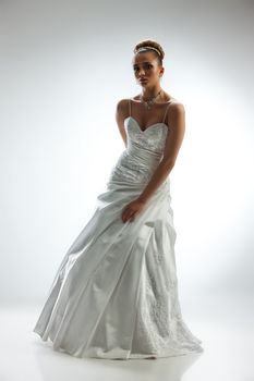 Young beautiful woman in a wedding dress on a studio background