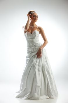 Young beautiful woman in a wedding dress on a studio background