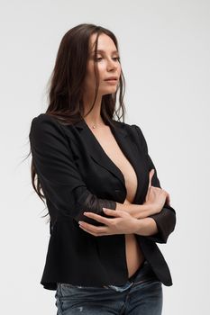 Hot brunette woman with naked breast touching black suit and provocatively looking away in studio
