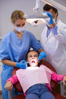Dentist and nurse examining a young patient with tools in clinic