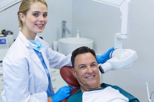 Portrait of dentist examining a male patient with dental tool in clinic