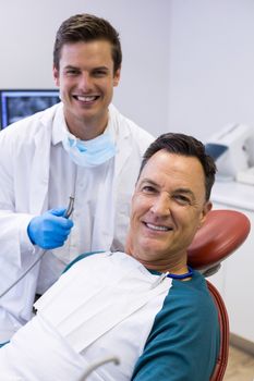 Portrait of dentist examining a male patient with tools in clinic