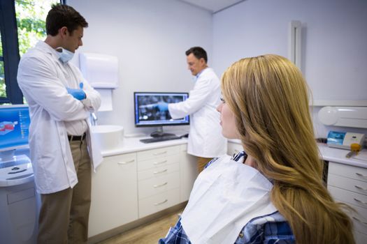 Dentist discussing teeth x-ray with his colleague and patient in clinic