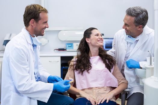 Dentist showing model teeth to patient in dental clinic