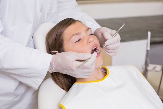 Pediatric dentist examining a patients teeth in the dentists chair at the dental clinic