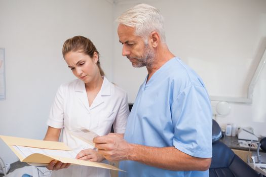 Dentist and assistant studying folder at the dental clinic